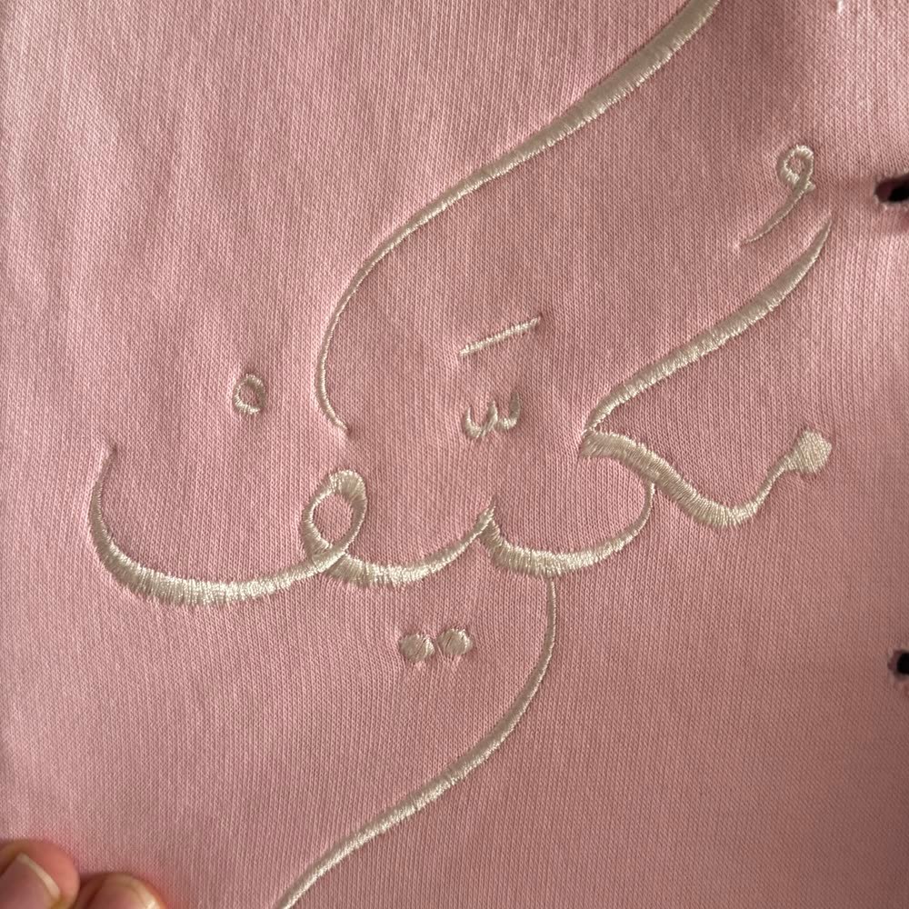 Bestickte arabische Kalligrafie auf rosa Textil